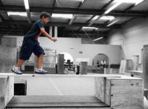 A boy is skateboarding on the ramp in an indoor facility.
