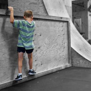 A boy standing on the side of a wall.