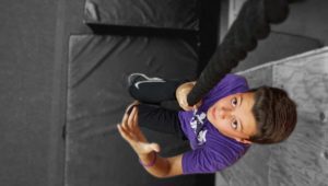 A young child holding onto a rope in the gym.