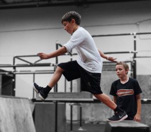 A boy and girl are skateboarding at the skate park.