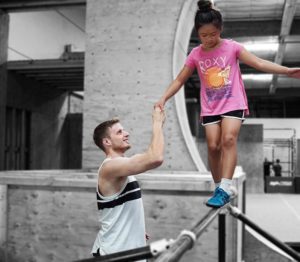 A man and girl are playing on the railing.