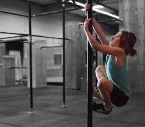 A woman is hanging on the bar in a gym.
