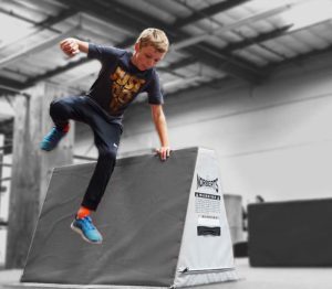 A boy is jumping over an obstacle course.