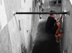 A young man hanging on to the railing of a wall.
