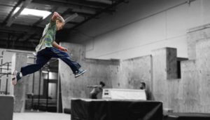 A man jumping in the air over an obstacle course.